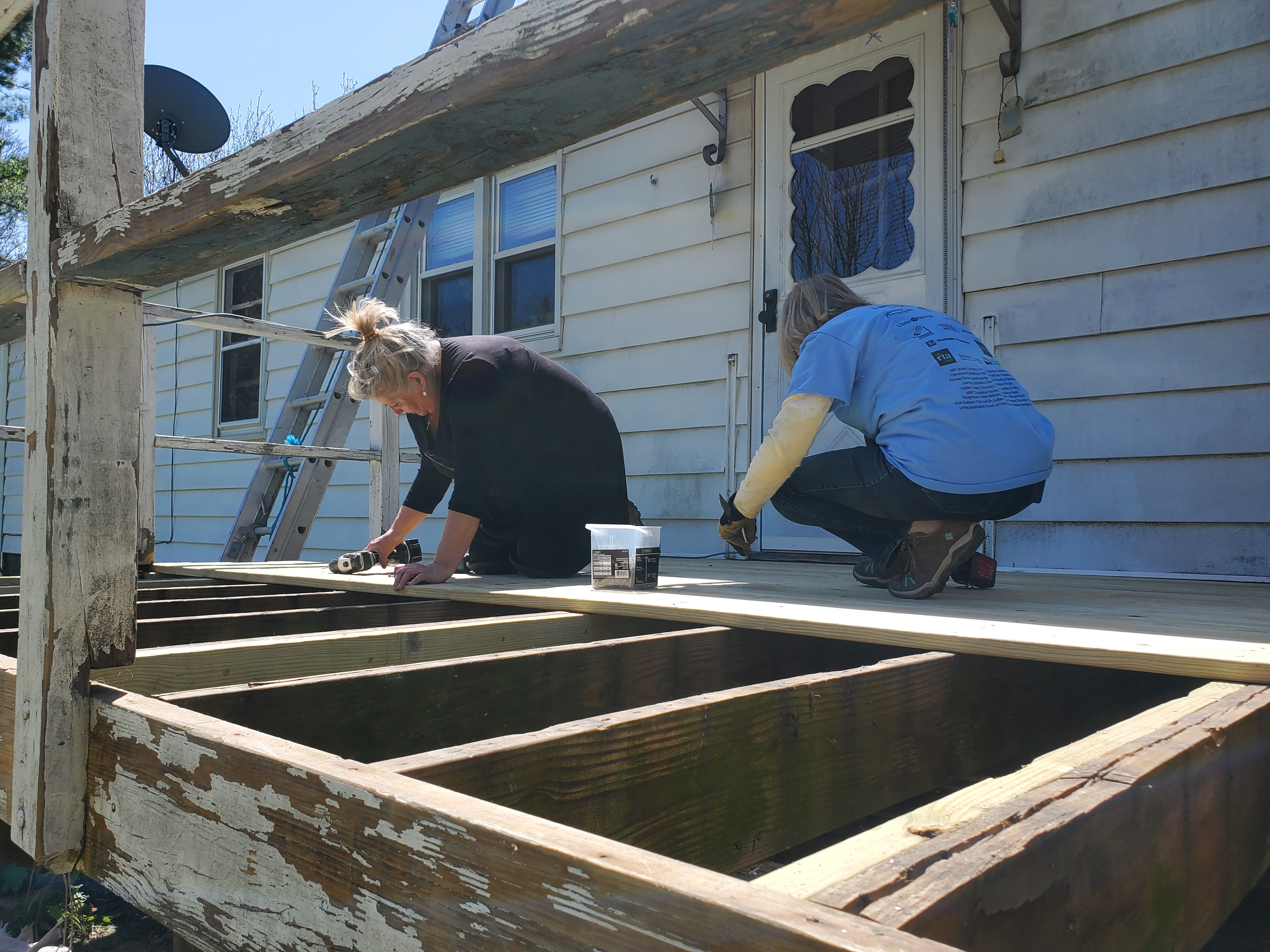Volunteers working hard on a deck in great need of repair.